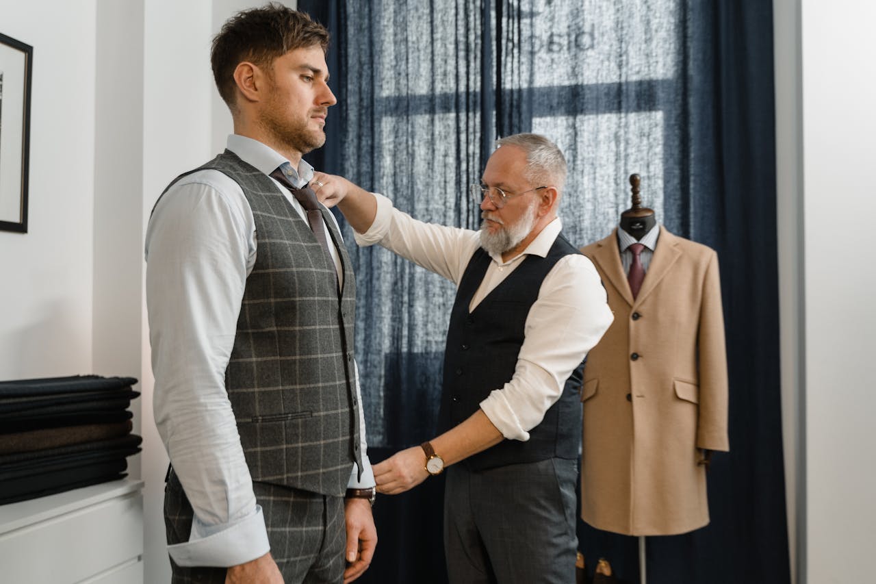 Skilled tailor adjusting a suit for a client in modern fashion atelier, showcasing bespoke tailoring.